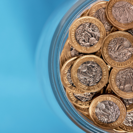 Pound coins in a tub on a blue background