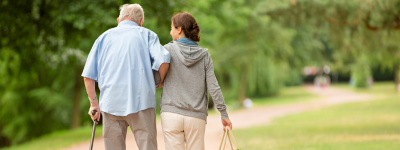 An older person being helped to walk by a younger person