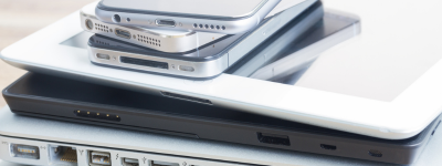 A stack of digital devices including phones and laptops