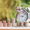 Stacks of coins in front of a clock.